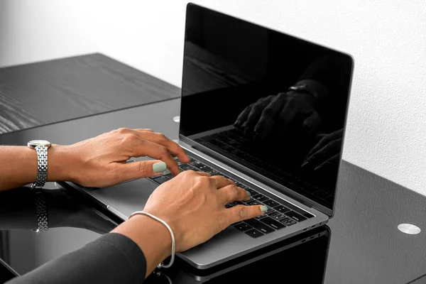 African American woman typing on a keyboard at a modern laptop