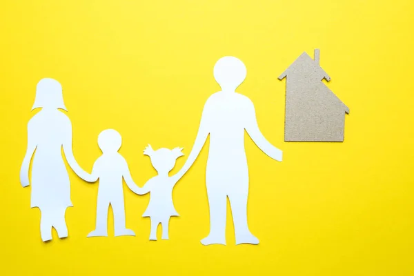 Modelo de casa y familia de papel aislado sobre fondo amarillo — Foto de Stock