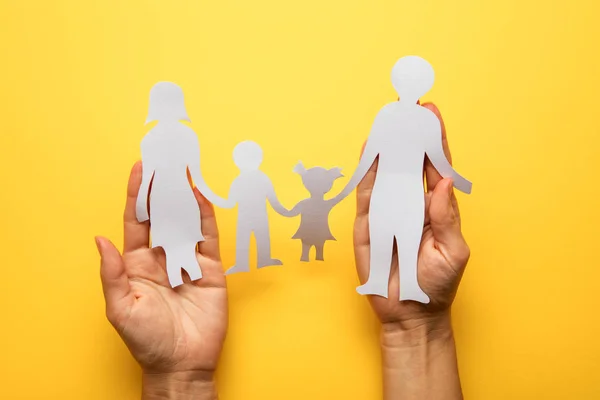 Paper family in hand isolated on yellow background