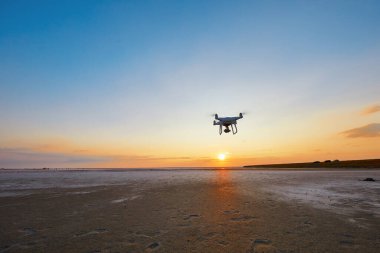 Deniz günbatımının arka planında uçan dron