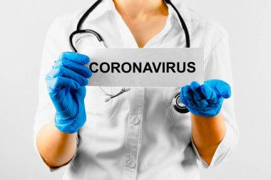 Coronavirus, üzerinde Coronavirus yazan beyaz kart beyaz önlüklü ve eldivenli doktorun ellerinde..