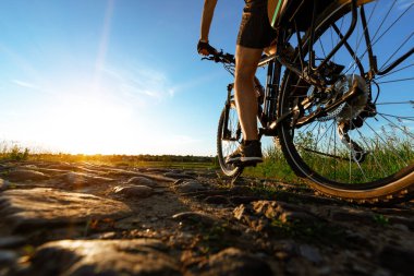Mavi gökyüzüne karşı bisikleti olan bir adamın arka görüntüsü. Bisikletçi bisiklet sürüyor..