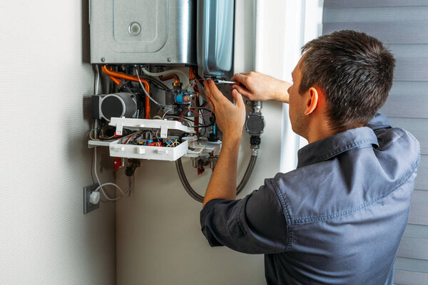 Plumber attaches Trying To Fix the Problem with the Residential Heating Equipment. Repair of a gas boiler