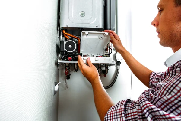 Plumber attaches Trying To Fix the Problem with the Residential Heating Equipment. Repair of a gas boiler