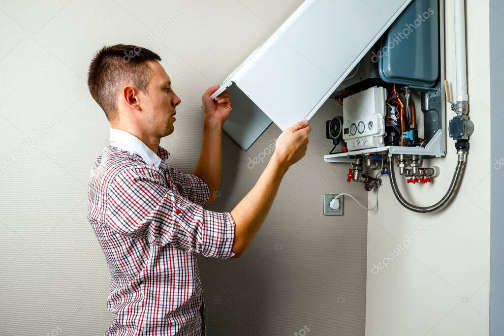 Plumber attaches Trying To Fix the Problem with the Residential Heating Equipment. Repair of a gas boiler