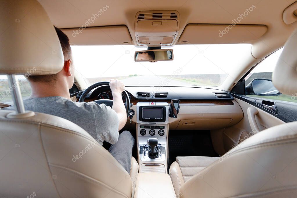 The young man driving the modern car on asphalt road