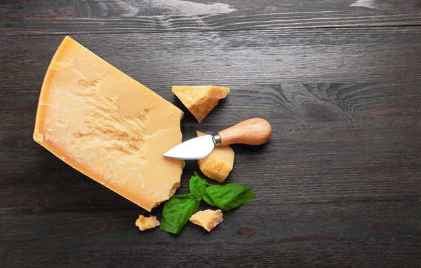 在有罗勒叶子的木板上的帕尔马奶酪 — 图库照片