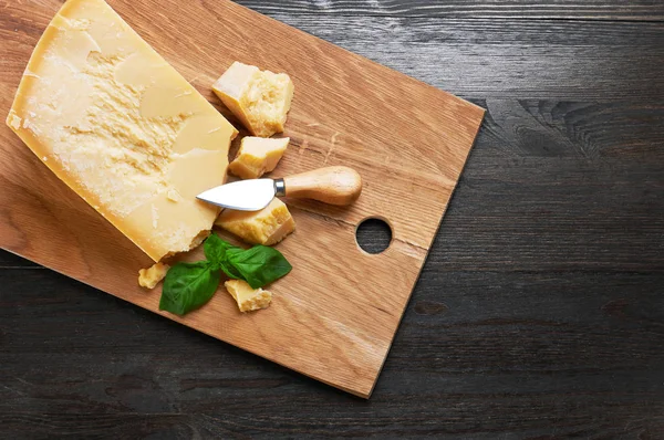 Parmesan cheese on wooden board with basil — Stock Photo, Image