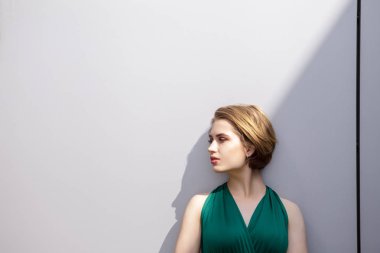 Bir duvar arka plan yeşil giysili bir kısa saç kesimi ile güzel bir genç kızın yüzü