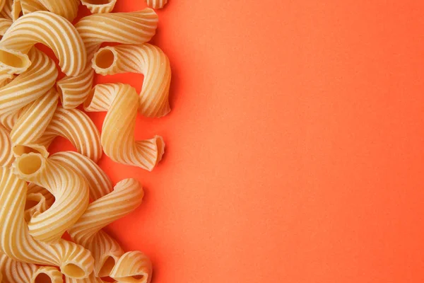 オレンジ色の背景にパスタ ペンネリガーテ 調理用原料 — ストック写真
