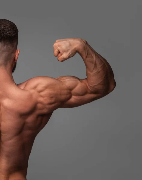 Schöner Kraftsportler Bodybuilder demonstriert seinen Bizeps. — Stockfoto