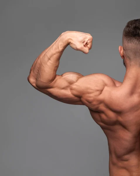 Bonito poder atlético homem fisiculturista demonstra seu bíceps. — Fotografia de Stock