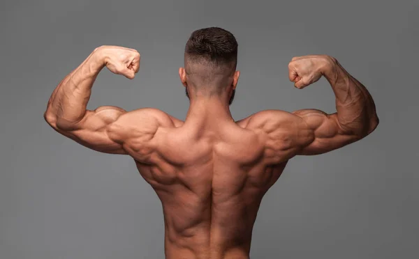 Muscular super-high level handsome man posing on gray background — Stock Photo, Image