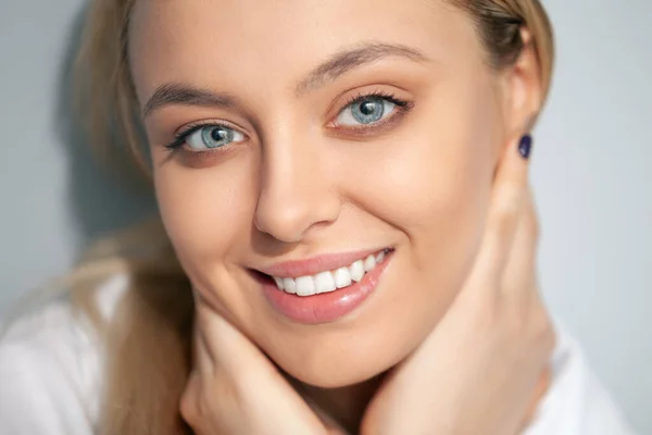 Portrait of a smiling blonde in a white blouse on a light background. — Stock Photo, Image