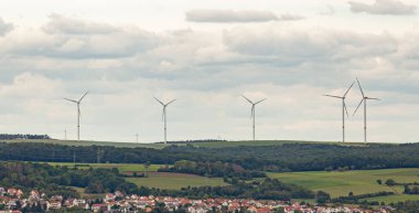 Bulutlu gökyüzünün arka planında rüzgar jeneratörleri.