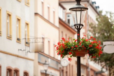 Çiçekli sokak lambası ve arka planda bir sokak.