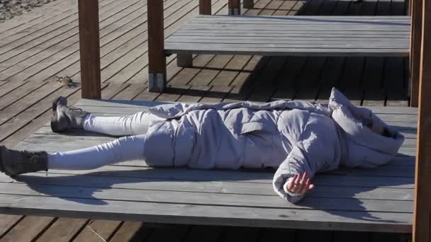海の近くのサンベッドで冬のジャケット日光浴の若い女性 冬休みのコンセプト — ストック動画