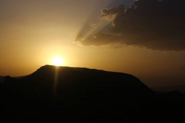 Güneş ışınları, güzellik bulutları ve siluetler ile dramatik gün batımı.