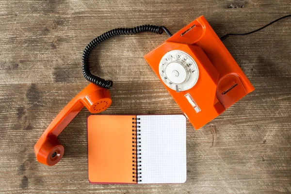 Παλιό Πορτοκαλί Τηλέφωνο Και Κενό Σημειωματάριο Ξύλινο Τραπέζι Άνω Όψη — Φωτογραφία Αρχείου