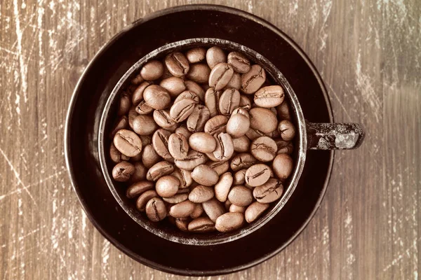 古い木の背景にコーヒー豆の完全なコーヒーカップ — ストック写真