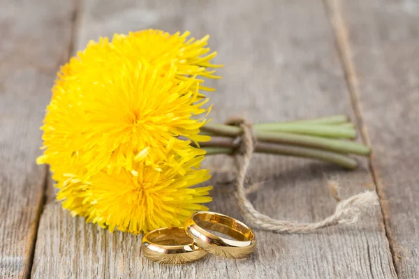 Wedding Rings Bunch Yellow Dandelion Flowers Wooden Background — Stock Photo, Image