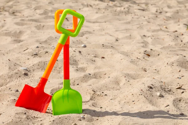 Δύο Πολύχρωμα Πλαστικά Φτυάρια Στην Άμμο Της Παραλίας — Φωτογραφία Αρχείου