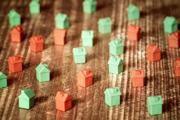 木制背景上的红色和绿色塑料玩具房子 房地产概念 — 图库照片
