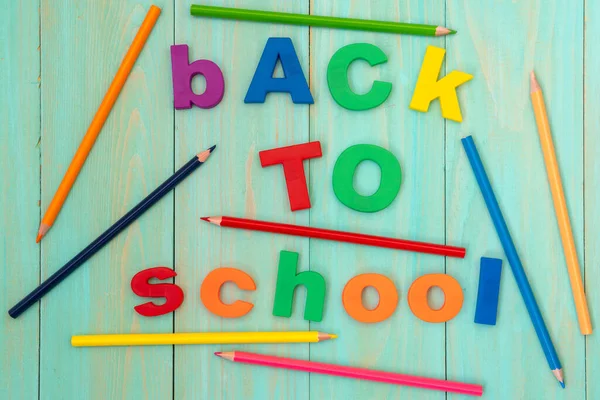 用一支色彩艳丽的铅笔在木制背景下返回学校 — 图库照片