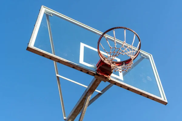 Basketball ring and board with white net. Low angle view. Sunny day. Clear sky.