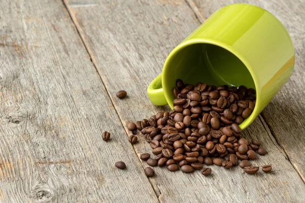 Groene Beker Met Verspreide Koffiebonen Houten Achtergrond — Stockfoto