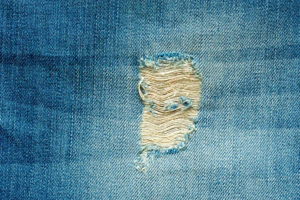 デニムジーンズの穴と糸 青いジーンズの背景をリッピング 青いジーンズの質感を閉じます — ストック写真