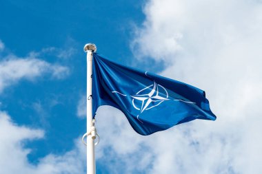 NATO flag waving in the wind against sky background clipart