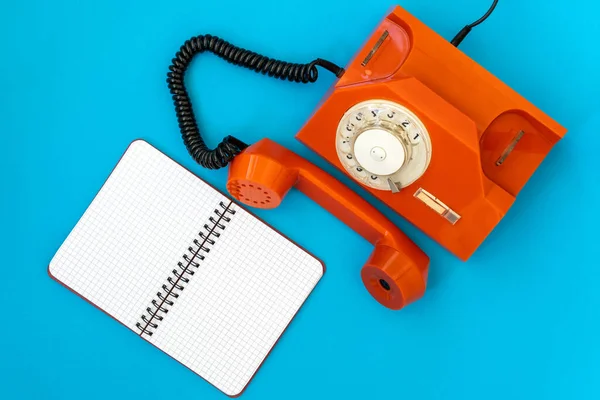 Vintage Pomarańczowy Telefon Pusty Notatnik Niebieskim Tle Widok Góry Podnieś — Zdjęcie stockowe