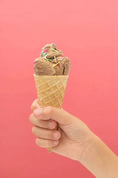 ピンクの明るい背景に手にアイスクリームコーン 夏のデザート — ストック写真