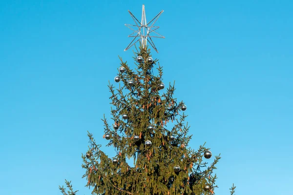 青空を背景に星型の装飾が施されたクリスマスツリーのトップ — ストック写真