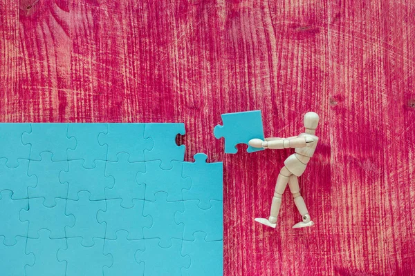 木制的人体模型 蓝色的拼图 粉色背景 建立商业成功 — 图库照片
