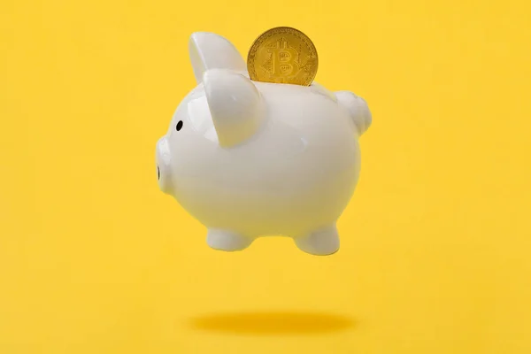 ピギーバンクとビットコインコイン黄色の背景の上に上昇 — ストック写真
