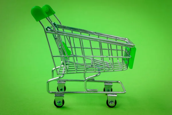 緑の背景にショッピングトロリー 買い物の準備 — ストック写真