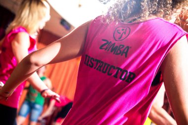 Pembe tişörtle dans eden Zumba eğitmeni.