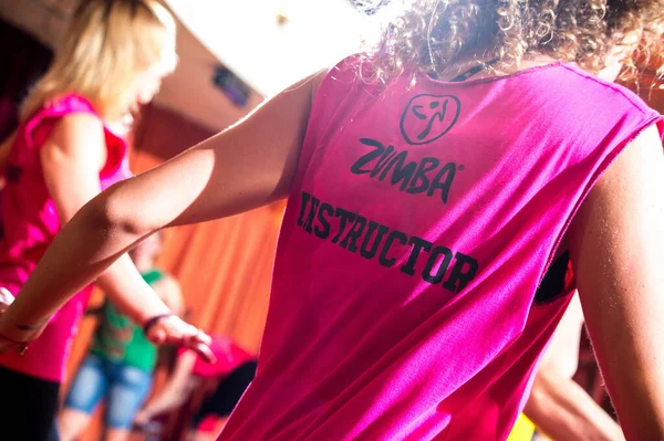 Pembe tişörtle dans eden Zumba eğitmeni.