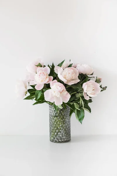 Bouquet of tender pink peonies in vase near white wall — Stock Photo, Image