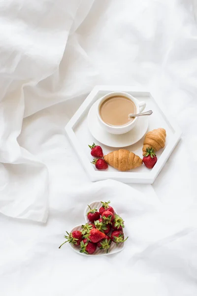 Ранній ранковий сніданок в ліжку, кава і круасан з соломою — стокове фото