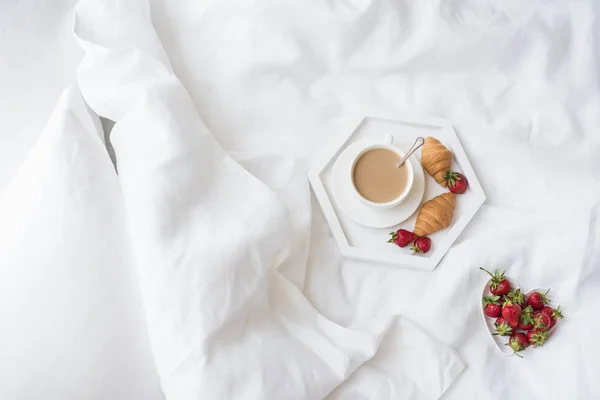 Ранний утренний завтрак в постели, кофе и круассан с клубникой — стоковое фото