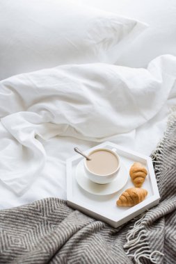 Rahat odaya yatak, fincan kahve ve kruvasan beyaz ve