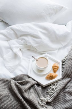 Rahat odaya yatak, fincan kahve ve kruvasan beyaz ve