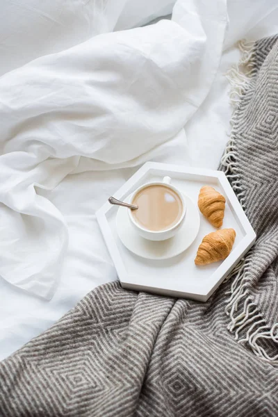 Cozy breakfast in bed, cup of coffee and croissants on white and — Stock Photo, Image