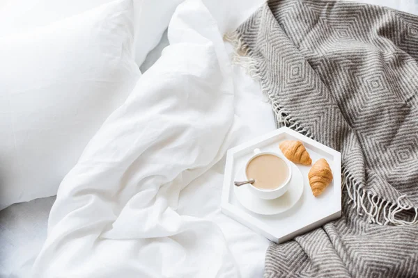 Ζεστό πρωινό στο κρεβάτι, φλιτζάνι καφέ και κρουασάν σε λευκό και — Φωτογραφία Αρχείου