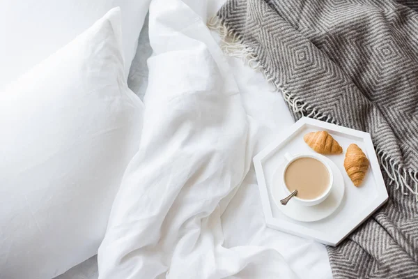 Petit déjeuner confortable au lit, tasse de café et croissants sur blanc et — Photo