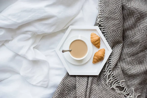 Gezellig ontbijt op bed, kopje koffie en croissants op wit en — Stockfoto