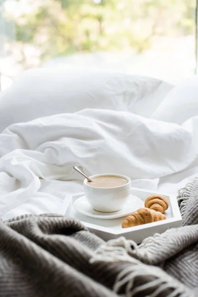 Petit déjeuner confortable au lit, tasse de café et croissants sur blanc et — Photo